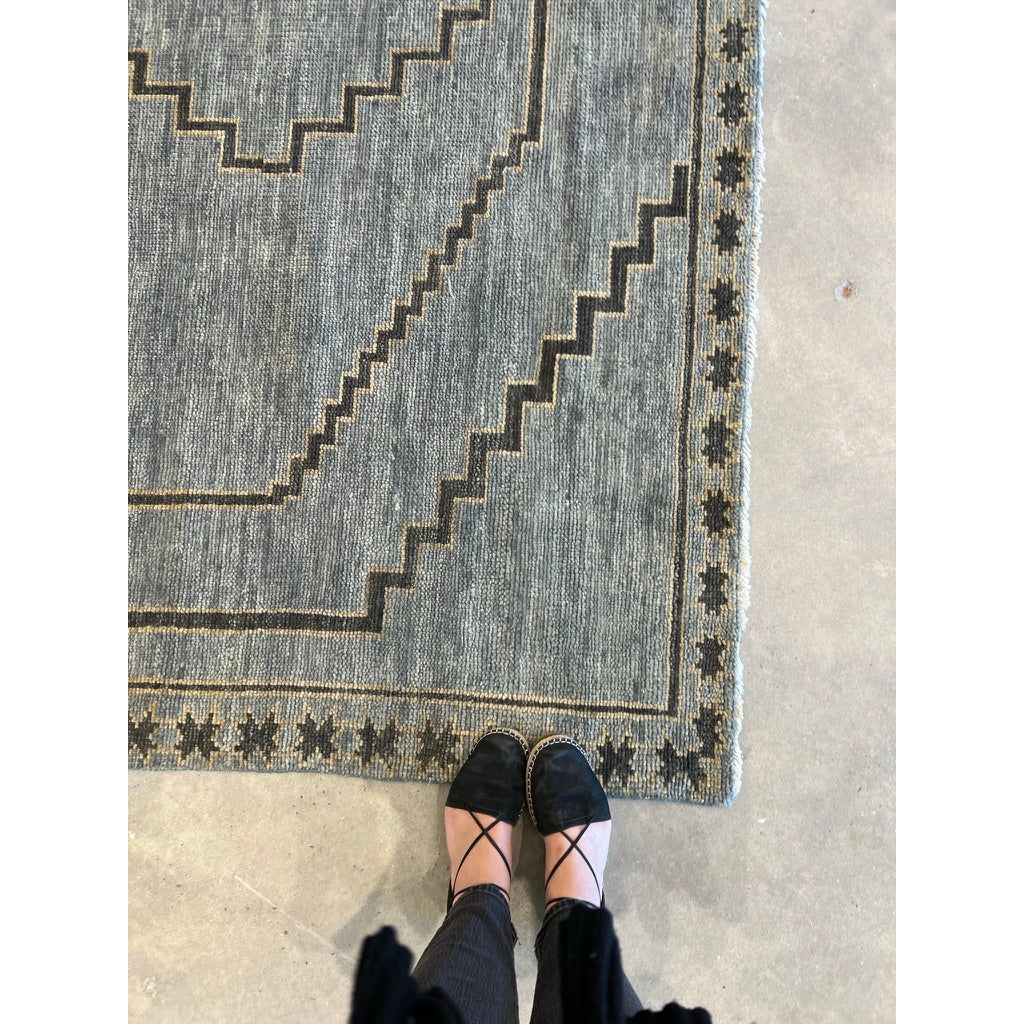 Featuring Cyprus Paphos Hand-Knotted Rug by Jaipur Living at Amethyst Home. The hand-knotted Cyprus collection showcases a modern representation of vintage Kars designs with clean-lined geometric details and fresh colorways. The blue, gray and sage green Paphos design delights with a minimalistic medallion pattern and a similarly styled border. Low pile and na.  Amethyst Home provides interior design, new home construction design consulting, vintage area rugs, and lighting in the Tampa metro area.