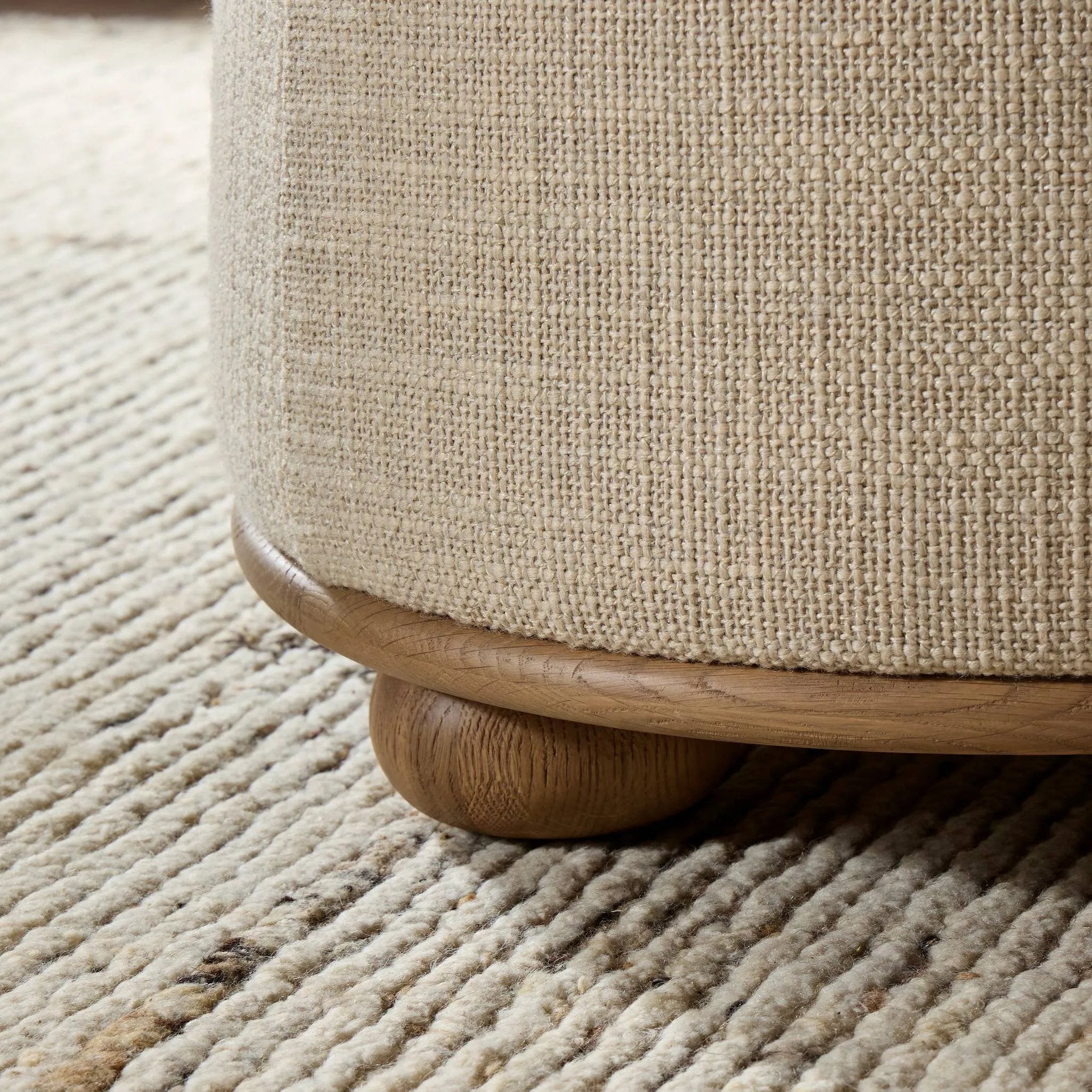 Featuring Bilbury Saxon Sand Ottoman by Four Hands at Amethyst Home. For an extra seat or propped feet, this welcoming ottoman features a subtly tapered shape and a rounded base with oak bun feet beneath. Crafted with soft foam cushioning and upholstered in a poly/wool blend fabric. Overall Dimensions: 22.00"w x 22.00"d x 18.50"h. Amethyst Home provides interior design, new home construction design consulting, vintage area rugs, and lighting in the Seattle metro area.