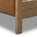 Slightly scooped top-grain leather tufting is bridged with metal bars in brushed brass for modern detailing. Aged smoked oak