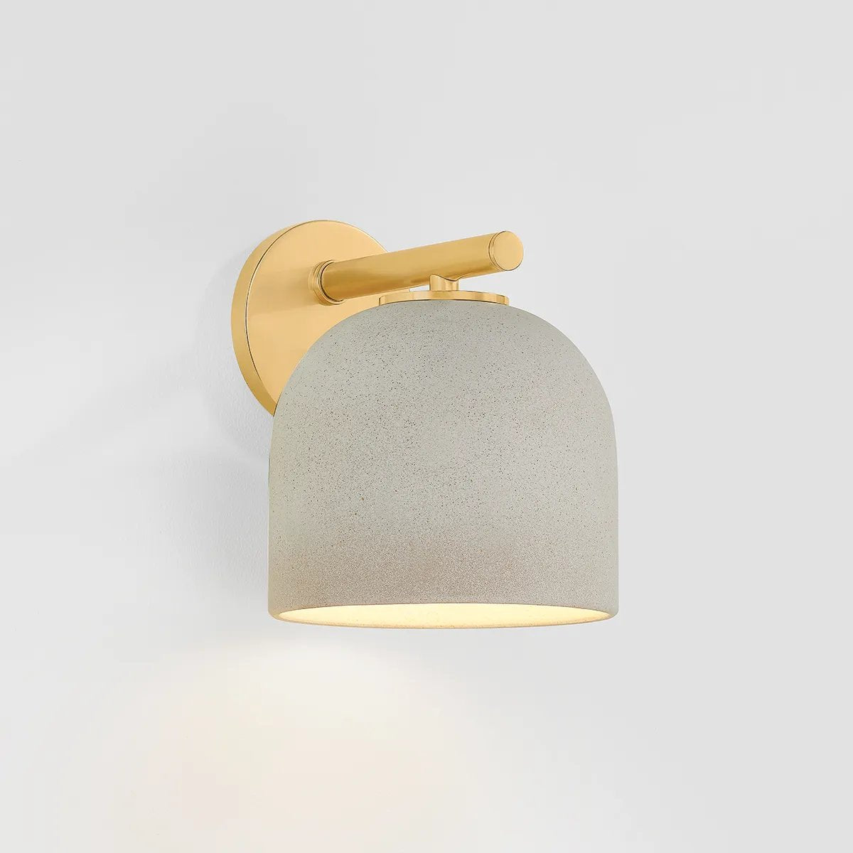 Inspired by Neoclassical architecture, Cara uses a domed shade and textural ceramic finish for a sconce that feels both ancient and new. A matte reactive glaze in an creamy hue creates a subtle surface grain that imitates natural stone. A circular modern armback in an Aged Brass finish adds shine to the fixture. Amethyst Home provides interior design, new home construction design consulting, vintage area rugs, and lighting in the Charlotte metro area.