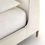 Welcome light, livable luxury into your bedroom with a fully upholstered bed. A tapered headboard features a fixed oversized cushion of high-performance fabric, creating a soft, layered look. Understated wooden legs complete the design. Amethyst Home provides interior design, new home construction design consulting, vintage area rugs, and lighting in the Charlotte metro area.