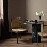 A steel dining chair frame is softened and paired with natural woven fibers. Thin, tapered legs and a tall channeled back cre