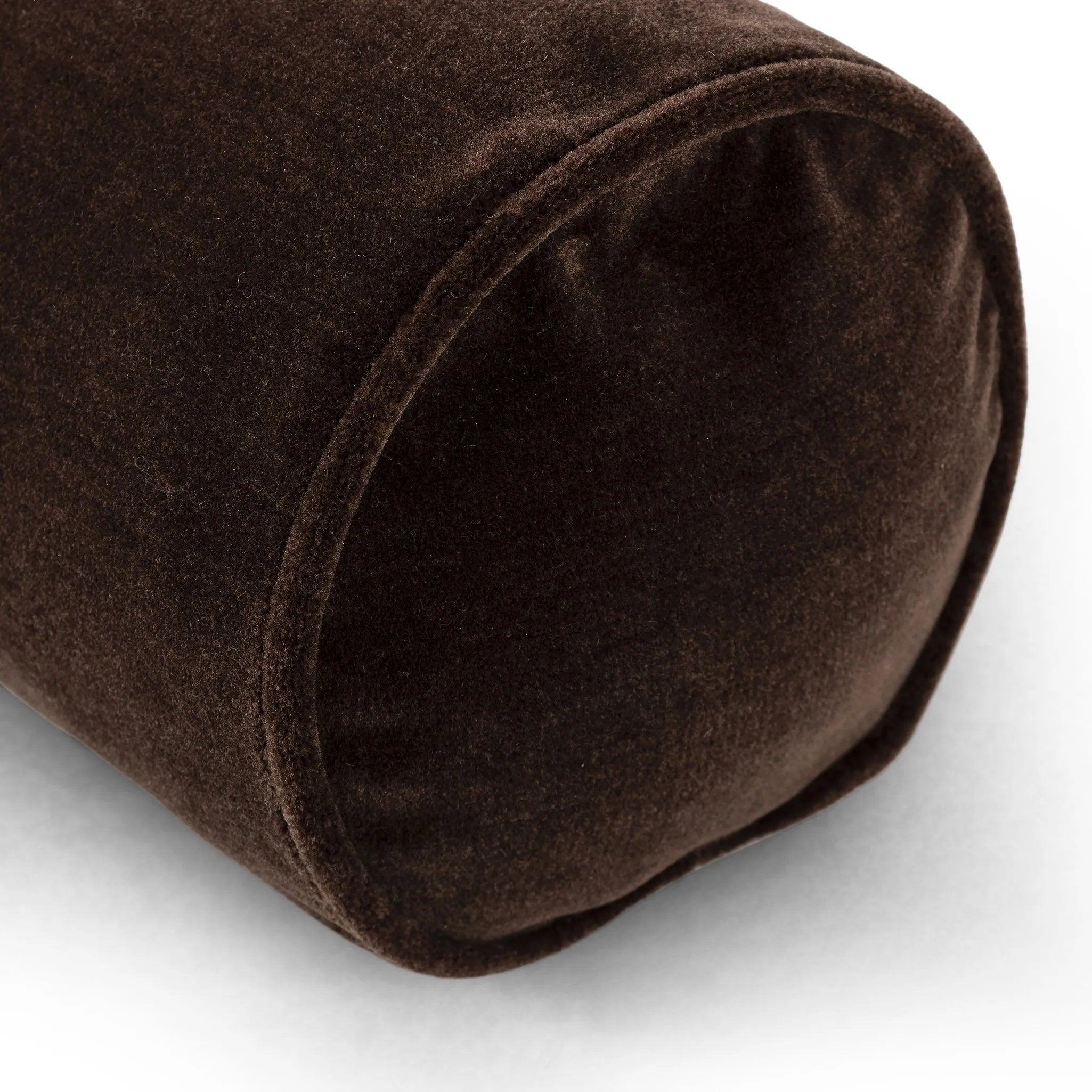 A long, chocolate-colored bolster pillow elevates beds and sofas in an instant. Crafted from saturated wool velvet, for a sustainable alternative to mohair, with a hidden zipper for a smooth silhouette Amethyst Home provides interior design, new home construction design consulting, vintage area rugs, and lighting in the Boston metro area.
