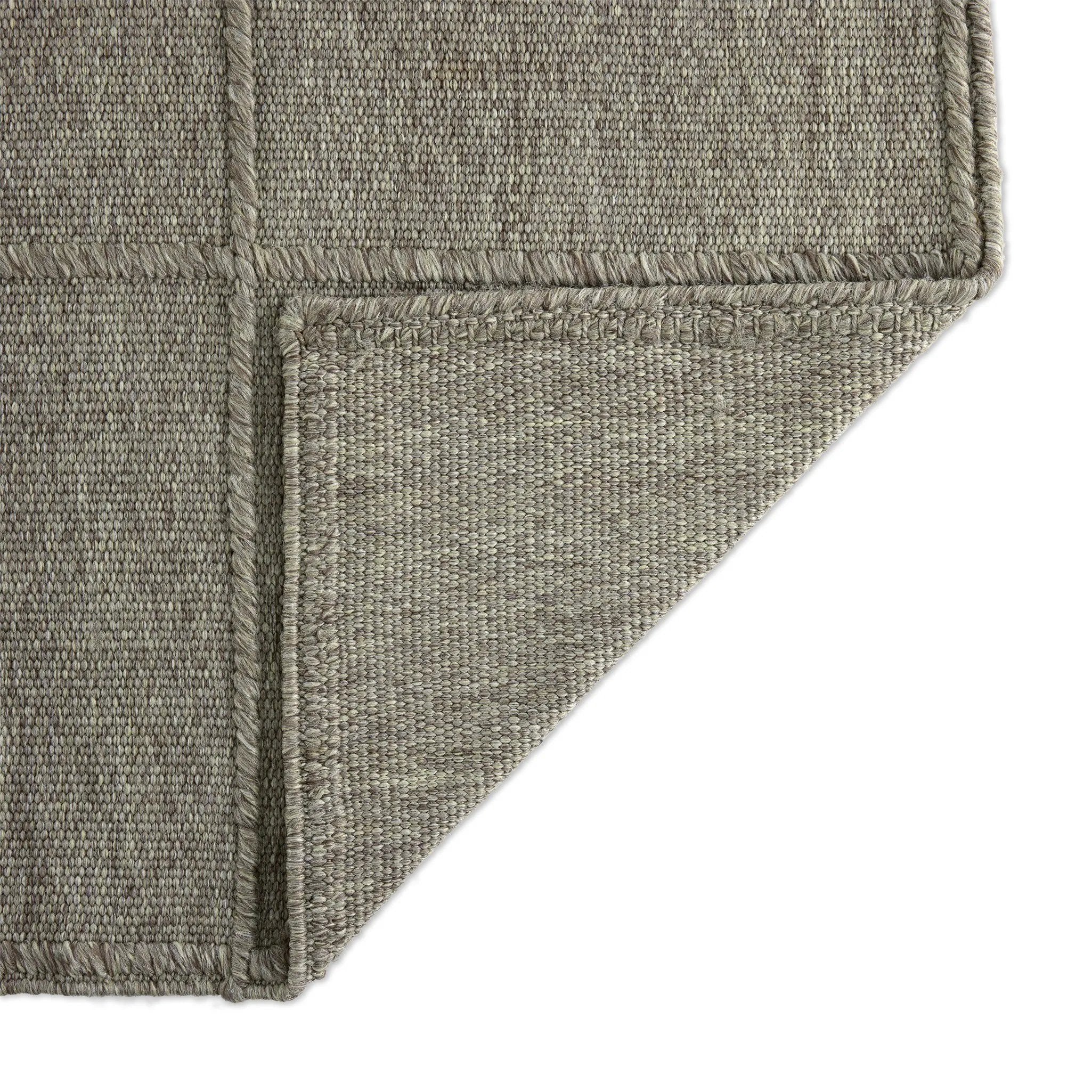Hand woven in a flat weave grid pattern for the look of an indoor textile, this  silver-hued rug grounds the outdoor lounge with a high-texture look. Slight variation in sizing and imperfect lines due to the handcrafted nature of each piece are to be expected. Store inside during inclement weather and when not in use. Amethyst Home provides interior design, new home construction design consulting, vintage area rugs, and lighting in the Los Angeles metro area.