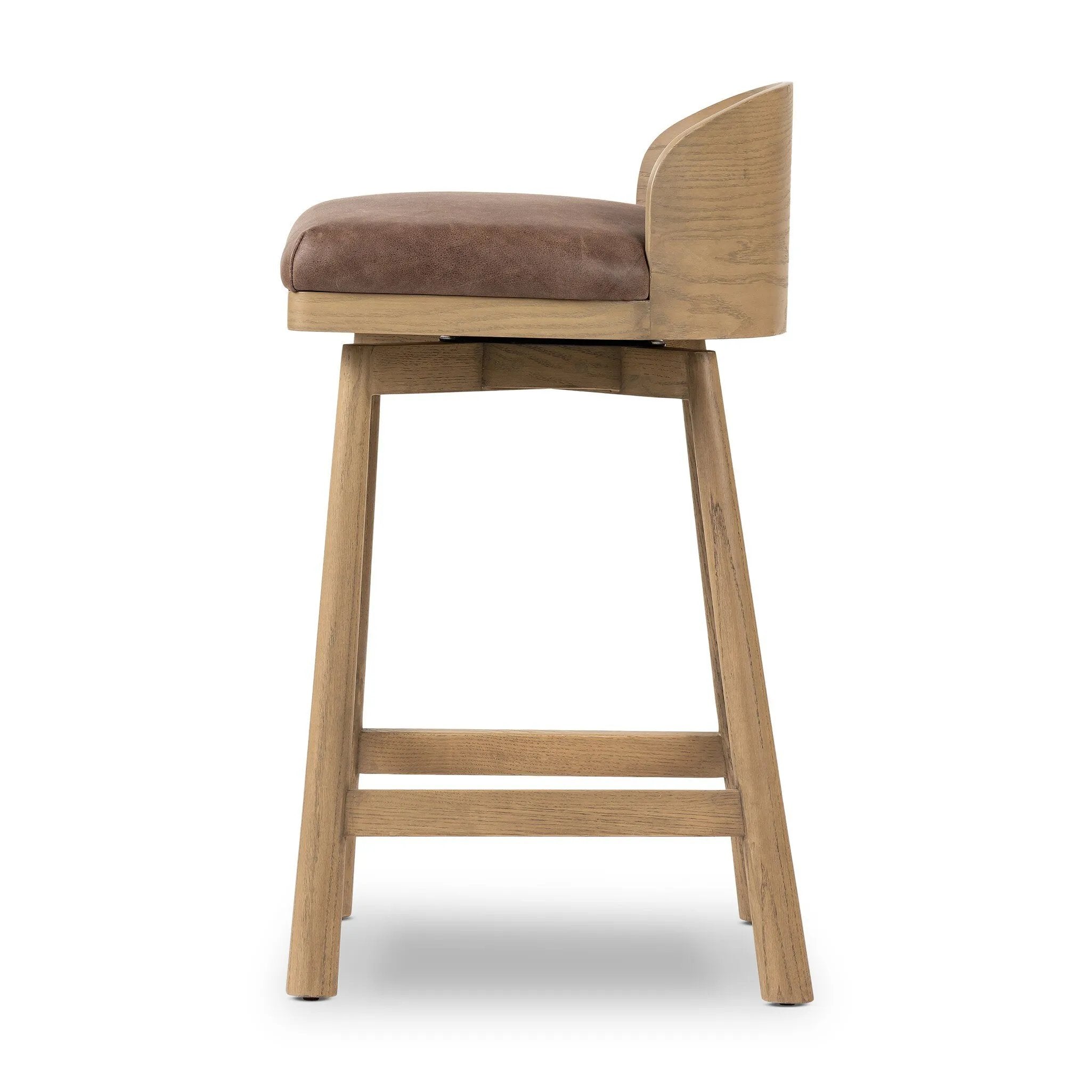 Featuring Cloris Palermo Cigar Swivel Bar + Counter Stool by Four Hands at Amethyst Home. Channel vintage vibes with a swivel stool perfectly sized for the bar. Crafted of blonde-finished oak, a low, molded back adds a playful touch, while a top-grain leather seat offers luxe comfort. Finished off with a memory swivel to ensure the stool's curved wood back. Amethyst Home provides interior design, new home construction design consulting, vintage area rugs, and lighting in the Alpharetta metro area.