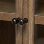 Featuring Dawes Weathered Oak Cabinet by Four Hands at Amethyst Home. Work the timeless charm of a vintage find into your collection. Weathered oak cabinetry features softened mullions and rounded glass panels, with aged bronze barrel hinges and finial detailing. Generous storage and display options  empower you to create a space that tells your story.Ove. Amethyst Home provides interior design, new home construction design consulting, vintage area rugs, and lighting in the Los Angeles metro area.