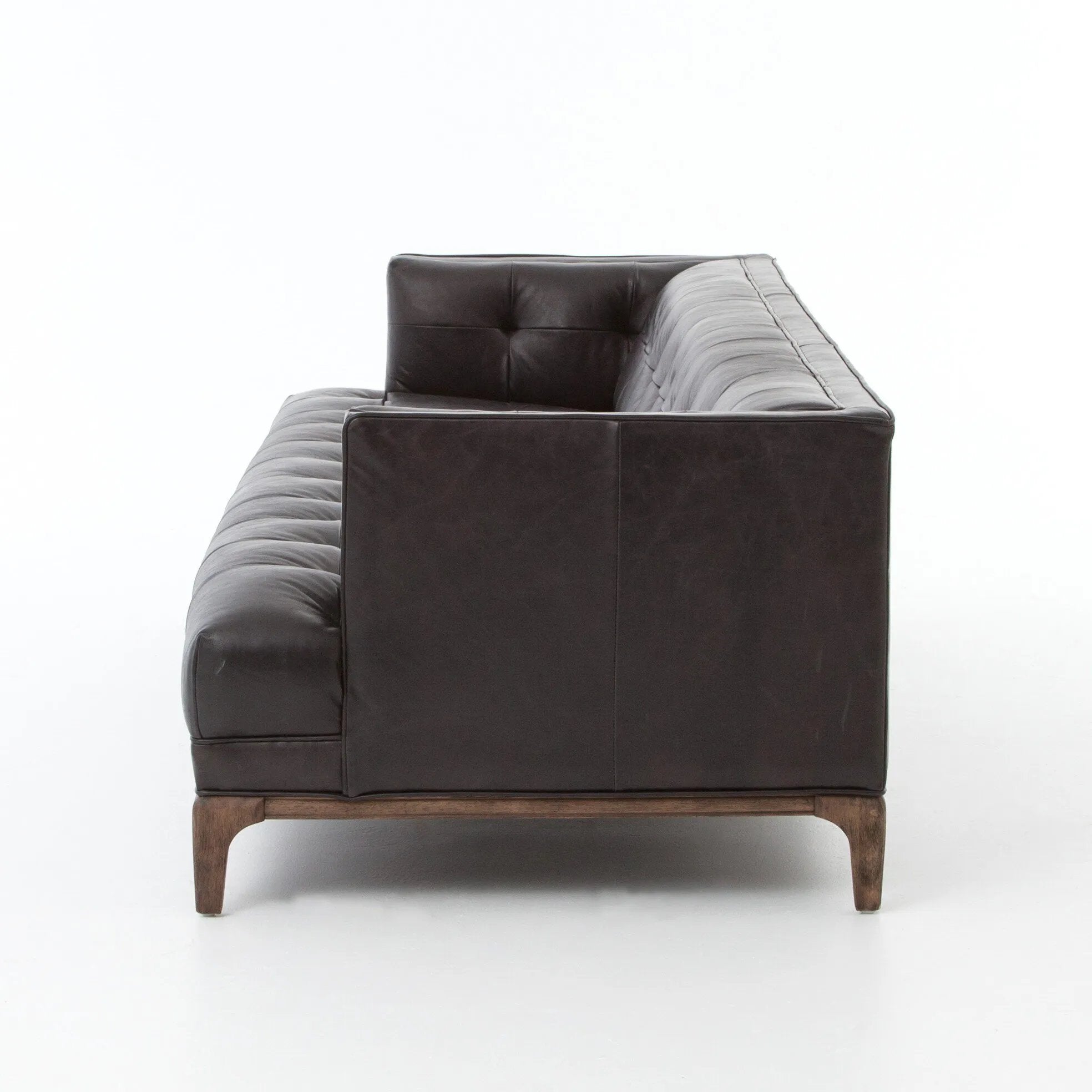 A modernized midcentury silhouette meets the traditional Chesterfield sofa, all in a compact profile perfect for smaller spaces. Top-grain leather in a classic black, button tufting and a smooth touch bring deep comfort to lounging Amethyst Home provides interior design, new home construction design consulting, vintage area rugs, and lighting in the Kansas City metro area.