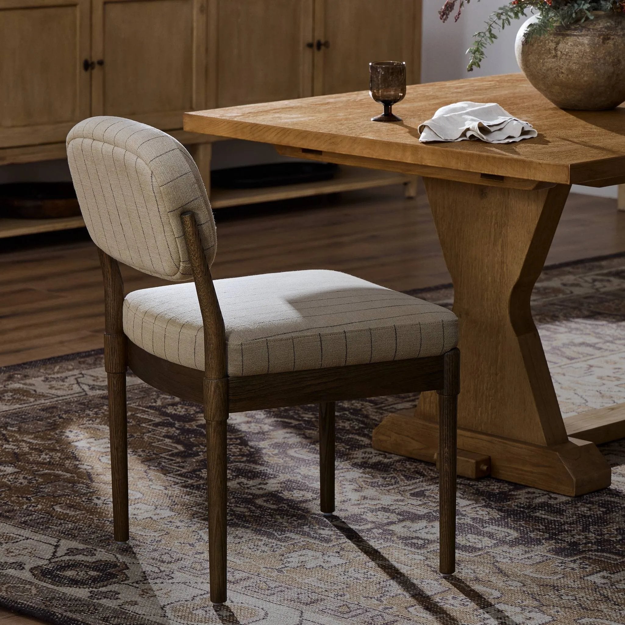 Modern materials place an updated twist on the traditional armless dining chair. Linen/cotton blend cushioning features a faint pinstripe for a unique-while-versatile look. Simply framed by brown oak Amethyst Home provides interior design, new home construction design consulting, vintage area rugs, and lighting in the Calabasas metro area.