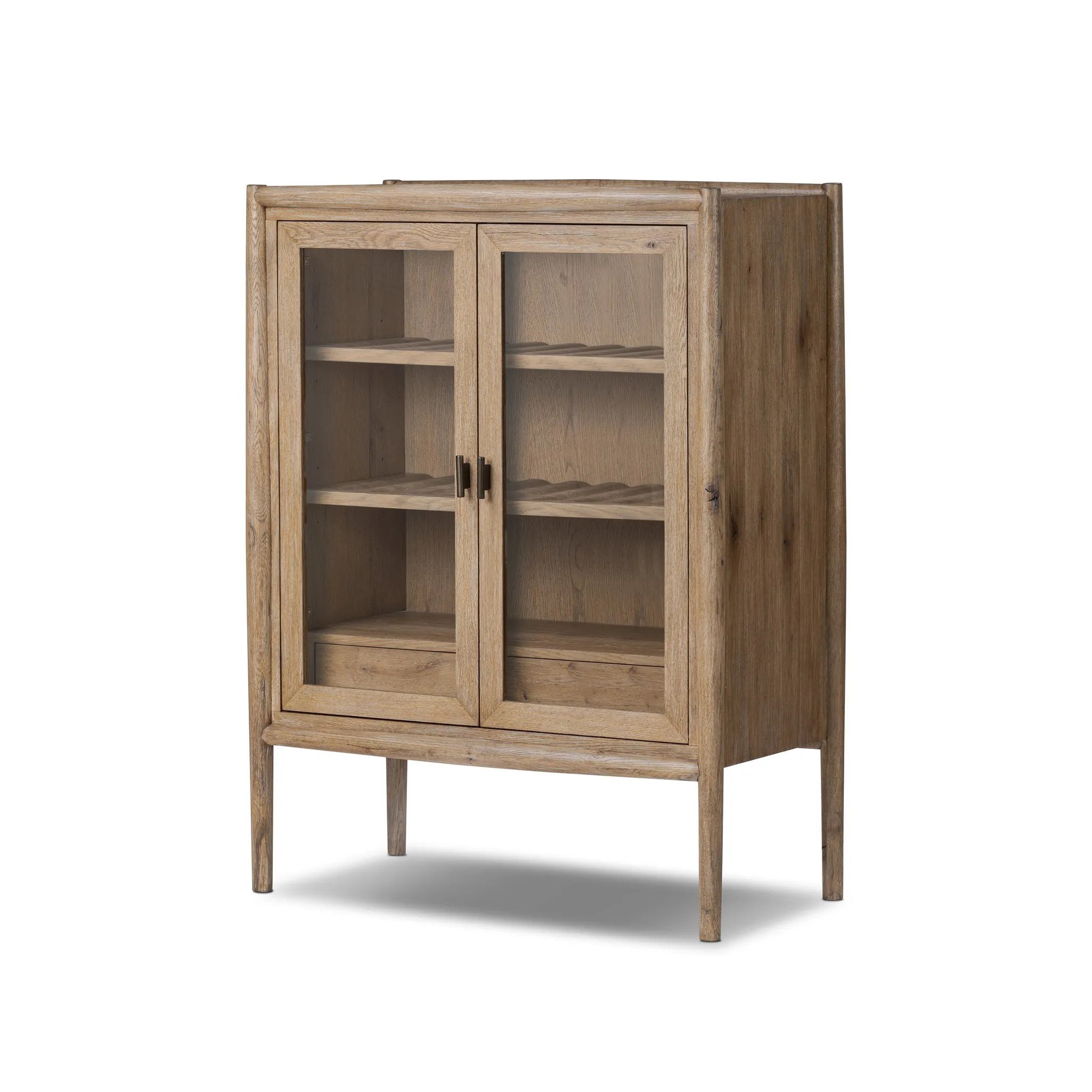 A rustic oak bar cabinet shapes subtly curved corners, bringing a handcrafted look to a minimalist form. Fixed center shelves, functional drawers and glass fronts for open display. Simple hardware is finished in an aged bronze Amethyst Home provides interior design, new home construction design consulting, vintage area rugs, and lighting in the Newport Beach metro area.