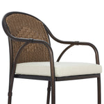 This outdoor dining chair takes inspiration from classic French bistro-style chairs, featuring a distinctive metal collar detail on the arms. The woven seatback comes together in a diamond pattern, finished with a cream-colored seat cushion. Cover or store inside during inclement weather and when not in use. Amethyst Home provides interior design, new home construction design consulting, vintage area rugs, and lighting in the Des Moines metro area.