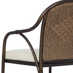 This outdoor dining chair takes inspiration from classic French bistro-style chairs, featuring a distinctive metal collar detail on the arms. The woven seatback comes together in a diamond pattern, finished with a cream-colored seat cushion. Cover or store inside during inclement weather and when not in use. Amethyst Home provides interior design, new home construction design consulting, vintage area rugs, and lighting in the Los Angeles metro area.