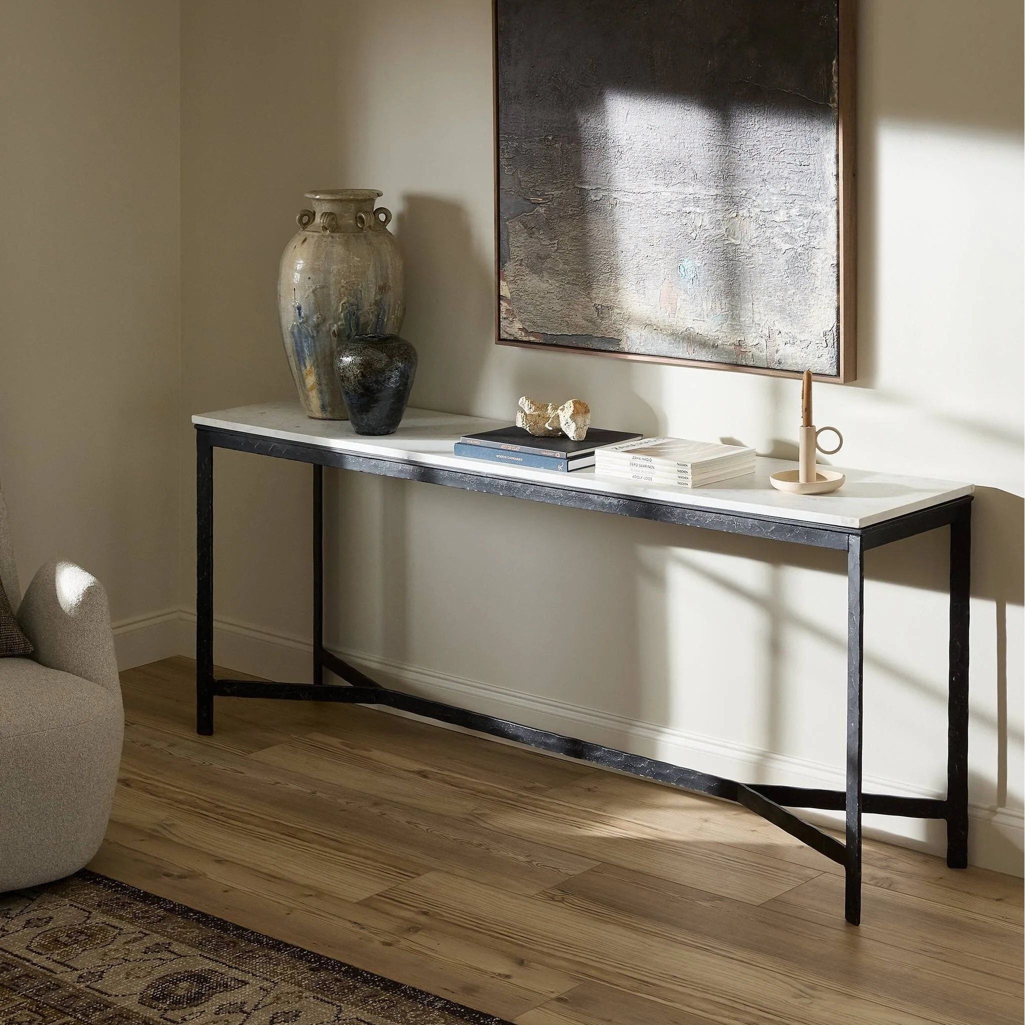 An open console table pairs a hand-hammered black iron base with a smooth white marble top, crafting a minimalist look with contrast. An open design creates endless possibilities for your media display and storage, or even styled in an entryway Amethyst Home provides interior design, new home construction design consulting, vintage area rugs, and lighting in the Boston metro area.