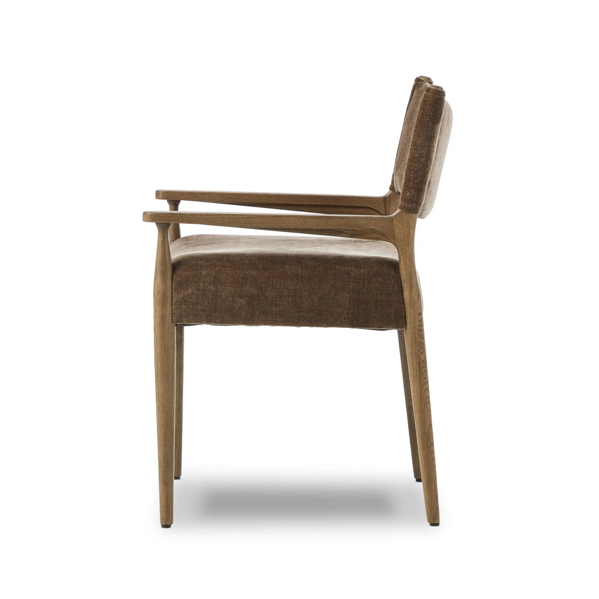 A midcentury-inspired piece brought to modern speed. A supportive, sling-style back and seat cushion are upholstered in a soft, velvety fabric, with toasted oak arms prime for the head of the table Amethyst Home provides interior design, new home construction design consulting, vintage area rugs, and lighting in the Miami metro area.