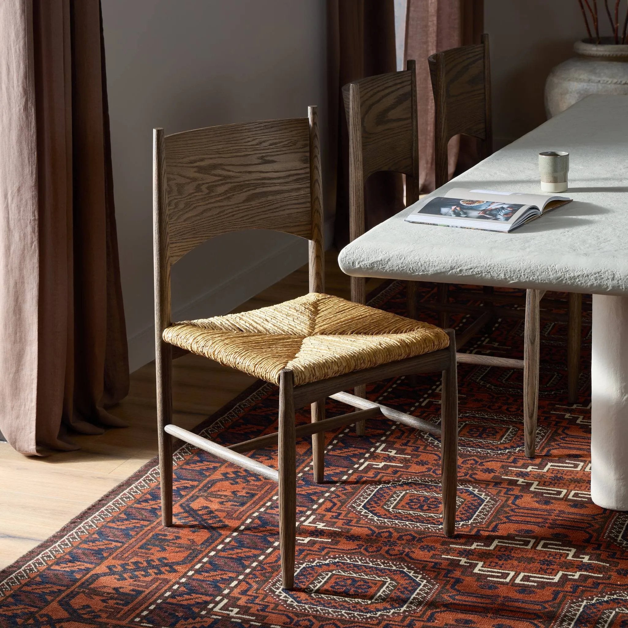 Featuring Jovan Stained Saddle Brown Dining Chair by Four Hands at Amethyst Home. A seamless addition to your dining collection, a slim-profile dining chair pairs a woven banana leaf seat with a solid oak frame featuring a bentwood back. Overall Dimensions: 20.00"w x 22.25"d x 37.00"h. Amethyst Home provides interior design, new home construction design consulting, vintage area rugs, and lighting in the Winter Garden metro area.