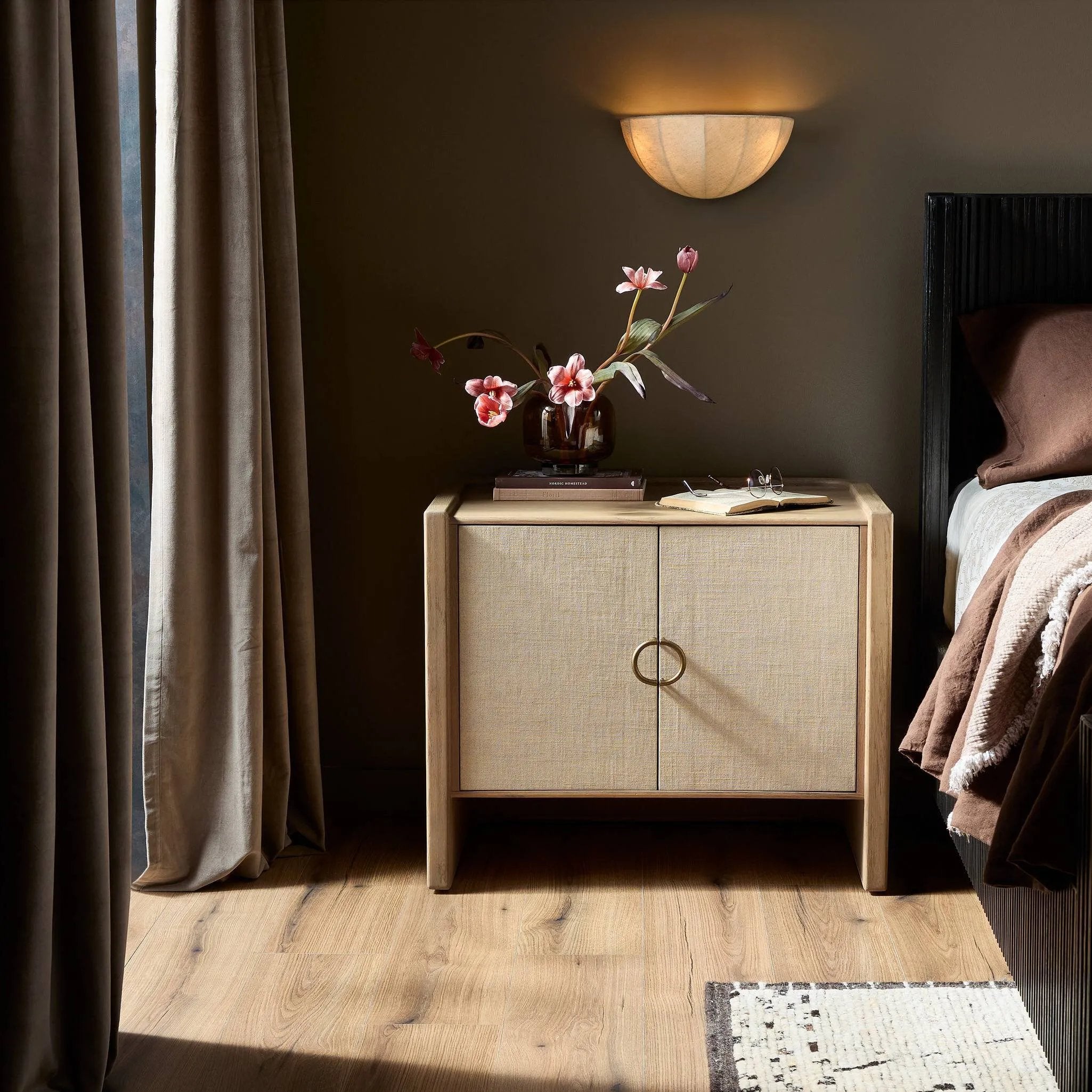Featuring Kiran Sandy Oak Veneer Nightstand by Four Hands at Amethyst Home. Bring storage to your bedside with a monochromatic nightstand of sandy oak and painted linen, with split-circle iron hardware. A spacious interior features removable shelving to custom suit your needs. Overall Dimensions: 30.00"w x 20.00"d x 25.00"h. Amethyst Home provides interior design, new home construction design consulting, vintage area rugs, and lighting in the Newport Beach metro area.