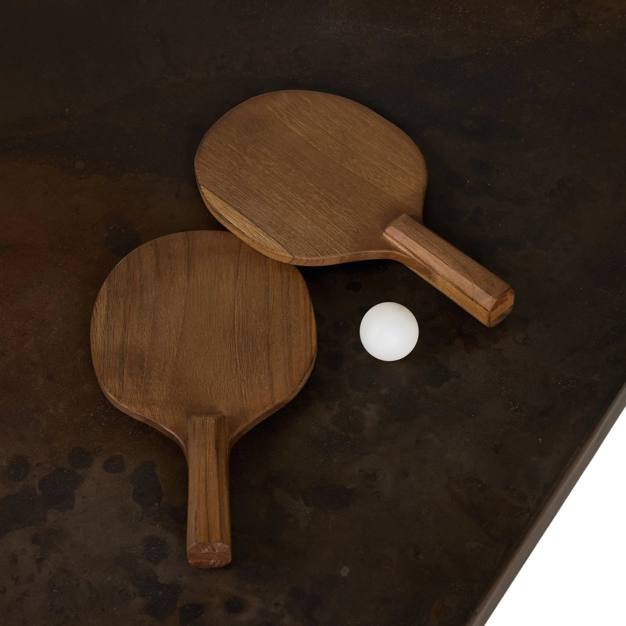 Outdoor-friendly and made for play, this ping pong table is clad in slatted teak and paired with a warm, tonal rust aluminum metal top with lots of visual movement. The teak net is removable, easily turning game time into dinner time. Includes four wooden paddles. Cover or store indoors during inclement weather and when not in use. Amethyst Home provides interior design, new home construction design consulting, vintage area rugs, and lighting in the Los Angeles metro area.