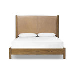 Rounded, chunky dowel legs in an amber oak finish frame the tan top-grain leather headboard of this simple-but-striking bed frame Amethyst Home provides interior design, new home construction design consulting, vintage area rugs, and lighting in the Austin metro area.