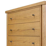 Create storage space in the bedroom with a five-drawer dresser of amber-finished oak. Chunky dowel legs support a tall silhouette and overhang top, all finished out with simple gunmetal hardware Amethyst Home provides interior design, new home construction design consulting, vintage area rugs, and lighting in the Dallas metro area.