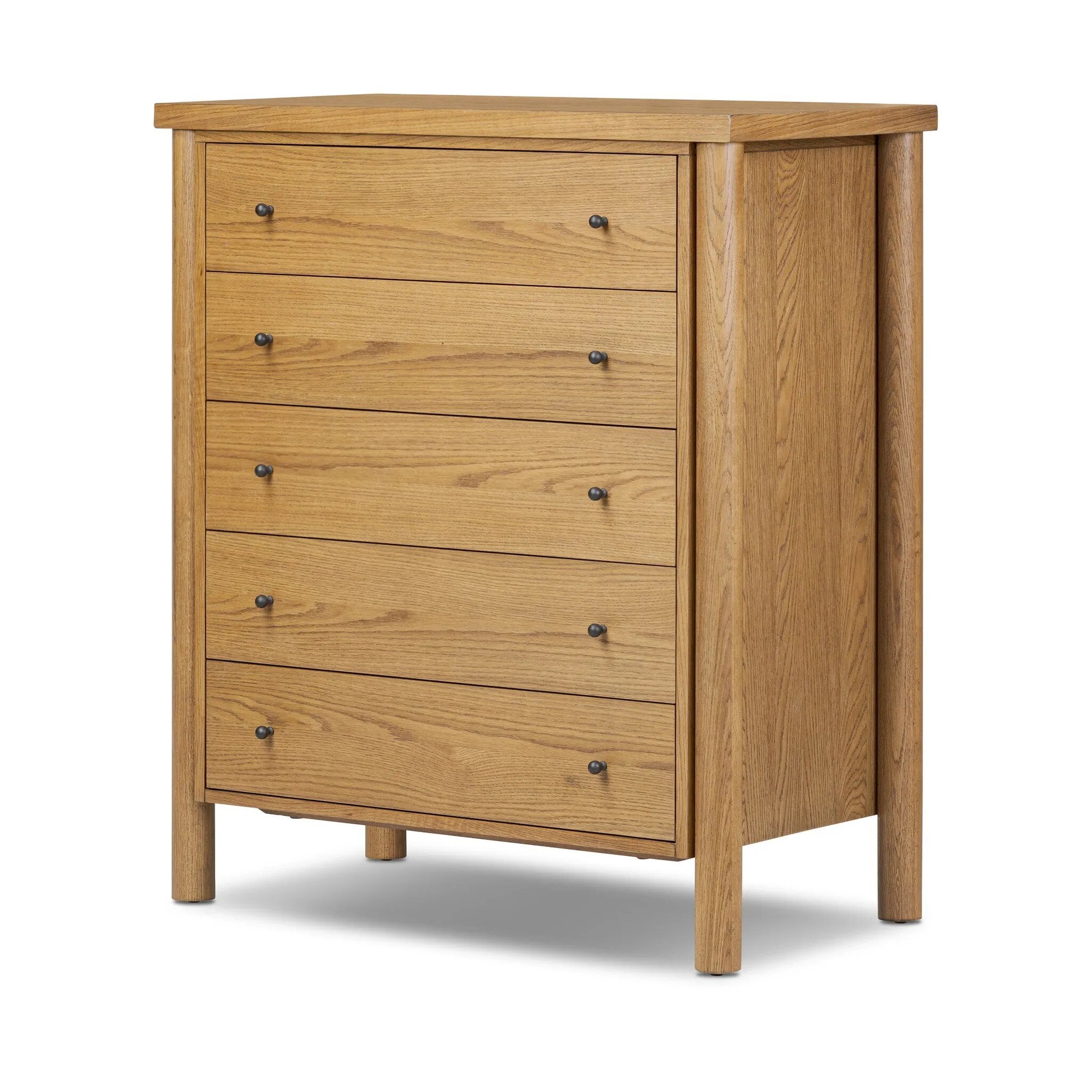Create storage space in the bedroom with a five-drawer dresser of amber-finished oak. Chunky dowel legs support a tall silhouette and overhang top, all finished out with simple gunmetal hardware Amethyst Home provides interior design, new home construction design consulting, vintage area rugs, and lighting in the Houston metro area.