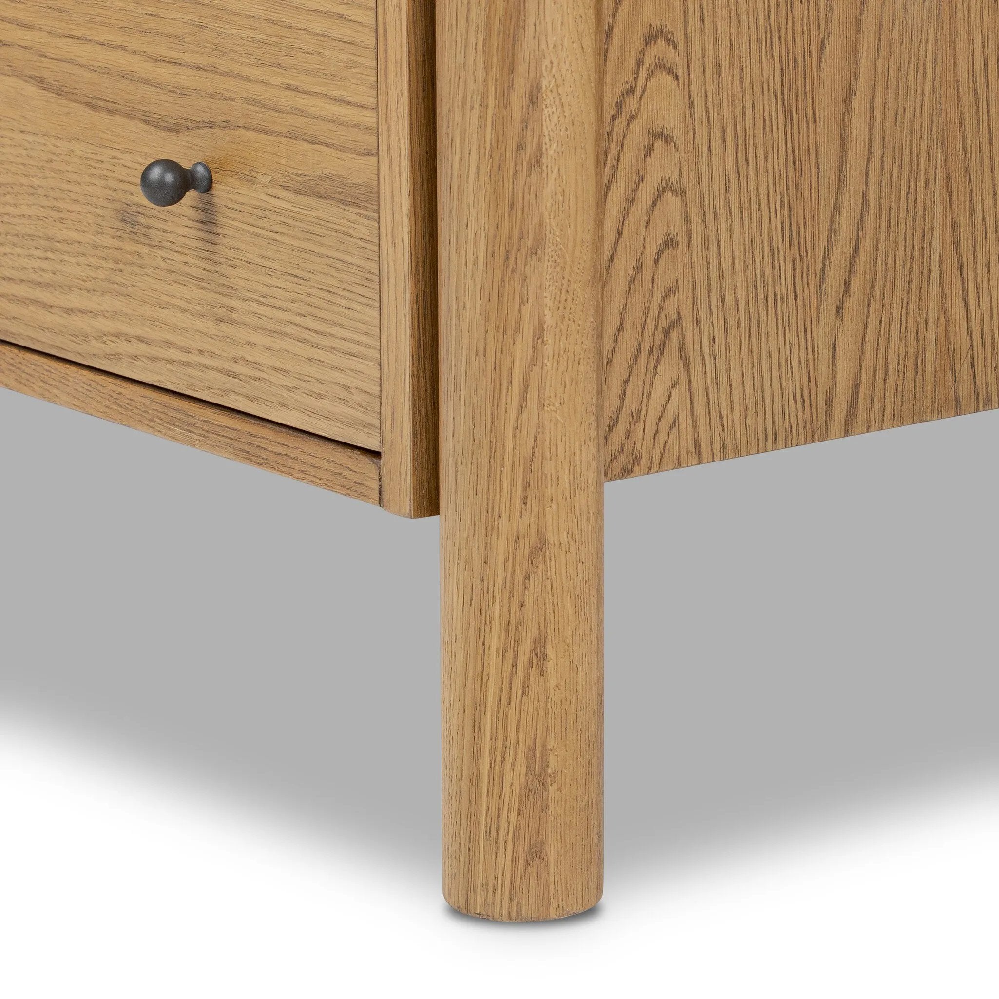 Create storage space in the bedroom with a five-drawer dresser of amber-finished oak. Chunky dowel legs support a tall silhouette and overhang top, all finished out with simple gunmetal hardware Amethyst Home provides interior design, new home construction design consulting, vintage area rugs, and lighting in the Nashville metro area.