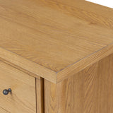 Create storage space in the bedroom with a five-drawer dresser of amber-finished oak. Chunky dowel legs support a tall silhouette and overhang top, all finished out with simple gunmetal hardware Amethyst Home provides interior design, new home construction design consulting, vintage area rugs, and lighting in the Newport Beach metro area.