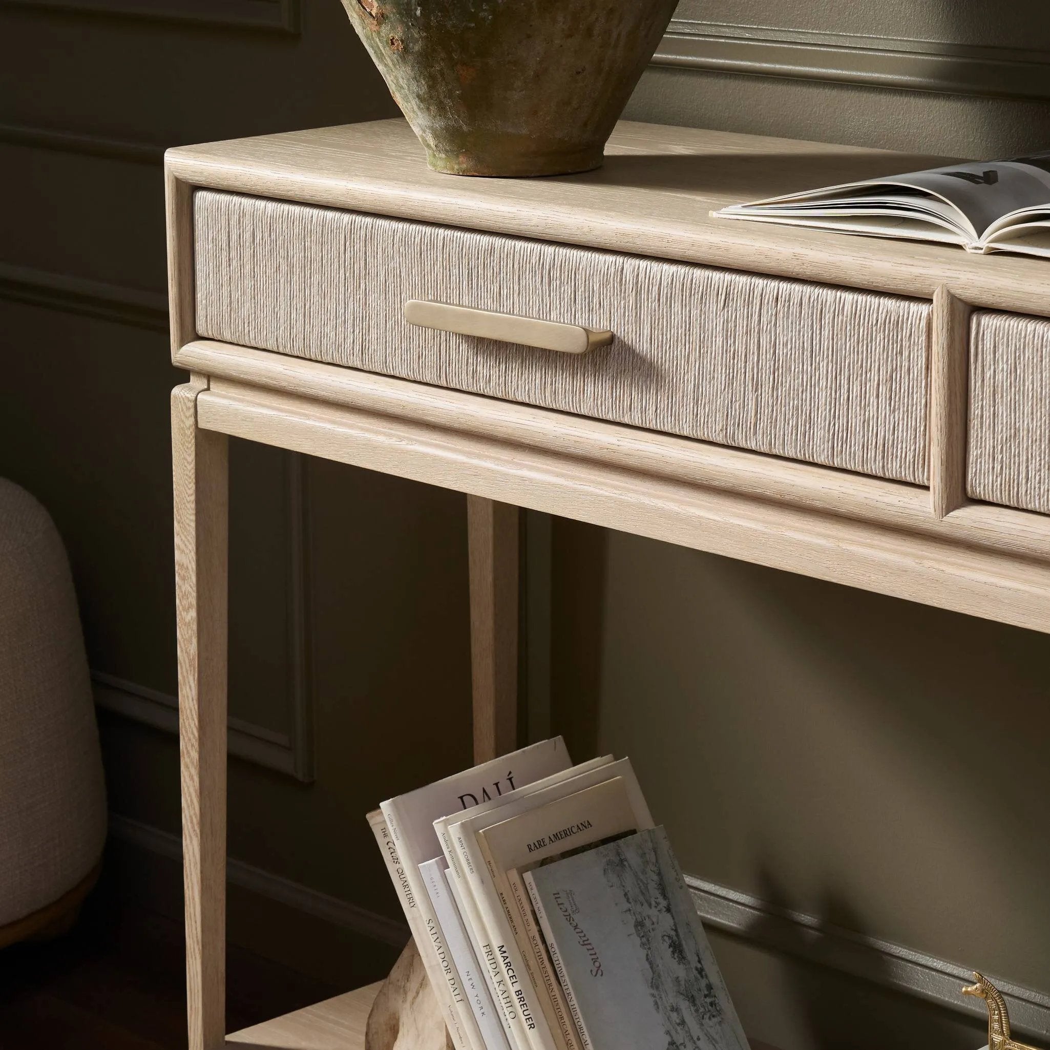 Elevate your living space or media room with a slim-profile console of light, natural oak. A smooth top pairs with two drawers covered with woven paper cord, while lower open shelving creates bonus storage and display options. The result: a clean, Scandinavian-inspired look that will work into your collection beautifully. Amethyst Home provides interior design, new home construction design consulting, vintage area rugs, and lighting in the Laguna Beach metro area.