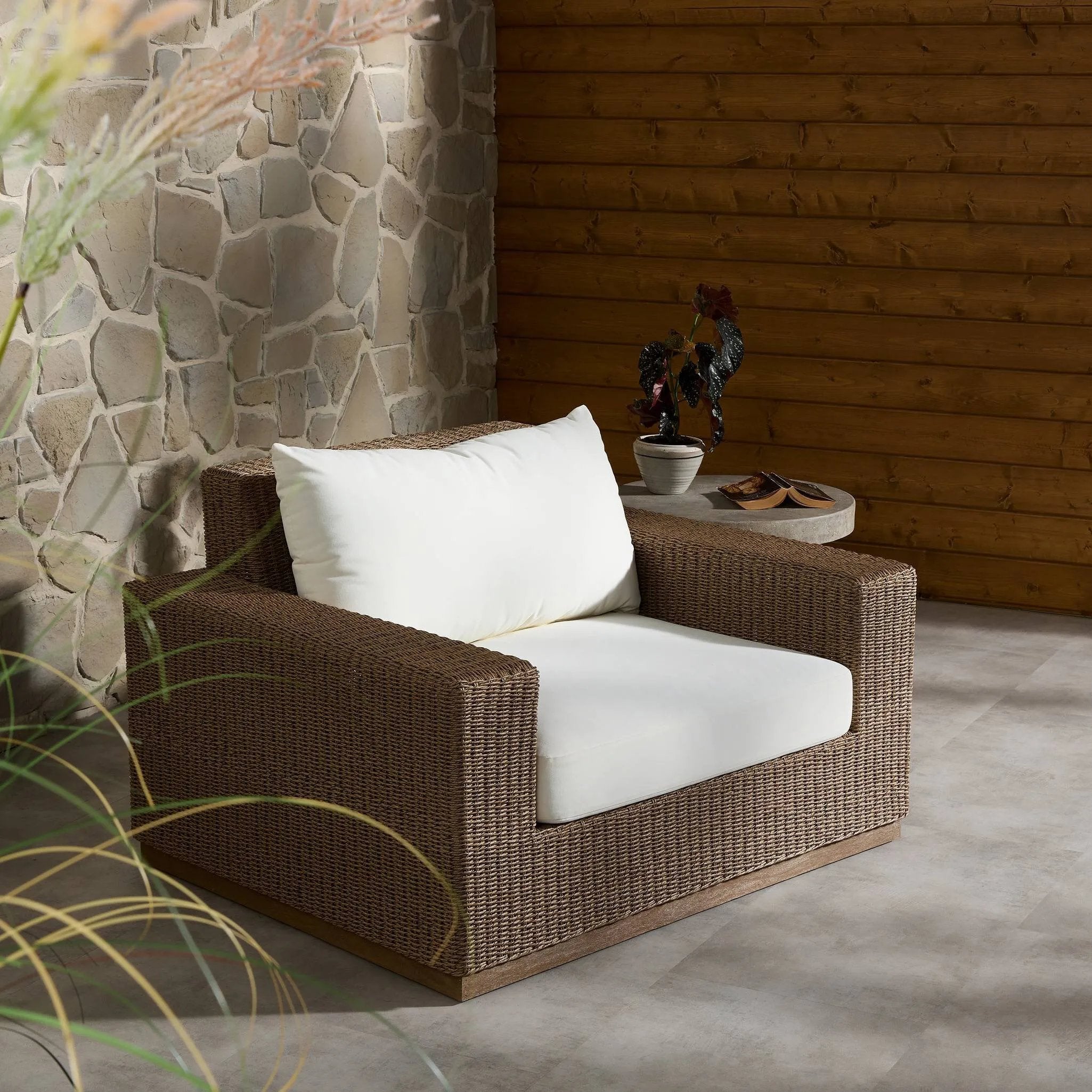 Elevate your outdoors. A wide-format outdoor chair features a faux hyacinth frame and plinth base. Linear details and a boxy silhouette make this piece truly timeless, while a knife-edge back  cushion softens the whole look. Upholstered in 100% olefin, known for its UV-resistant, water-repellent and quick-drying abilities. Amethyst Home provides interior design, new home construction design consulting, vintage area rugs, and lighting in the Omaha metro area.