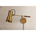 Tailored task lighting, this portable, functional swing arm sconce is also thoughtfully designed and beautiful. The sleek arm features a wooden handle on one end and an adjustable metal shade in Patina Brass or Bronze on the other. The twisted black cord detailing at the shade and backplate give Novel a nostalgic feel. Amethyst Home provides interior design, new home construction design consulting, vintage area rugs, and lighting in the Washington metro area.