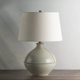 Inspired by rustic pottery, this table lamp's beautifully shaped base is crafted of pale sage ceramic giving it an earthy pale green tone. The off white linen shade pairs naturally and casts a soft glow. Raised seamlines and a reactive glaze that allows hints of the natural ceramic to peek through, give the fixture a hand-thrown, crafted feel. Amethyst Home provides interior design, new home construction design consulting, vintage area rugs, and lighting in the Portland metro area.