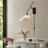 Featuring Hassell Jet Black Sconce by Four Hands at Amethyst Home. A flax linen shade with subtle flecking pairs with a sleek black metal body and dark walnut handle. Dual points of articulation including a horizontal arm rotation and vertical shade adjustment ensure precise light positioning. The plug-in design features a cord-concealing pipe and wall-mounted backplates for a r. Amethyst Home provides interior design, new construction, custom furniture, and area rugs in the Kansas City metro area
