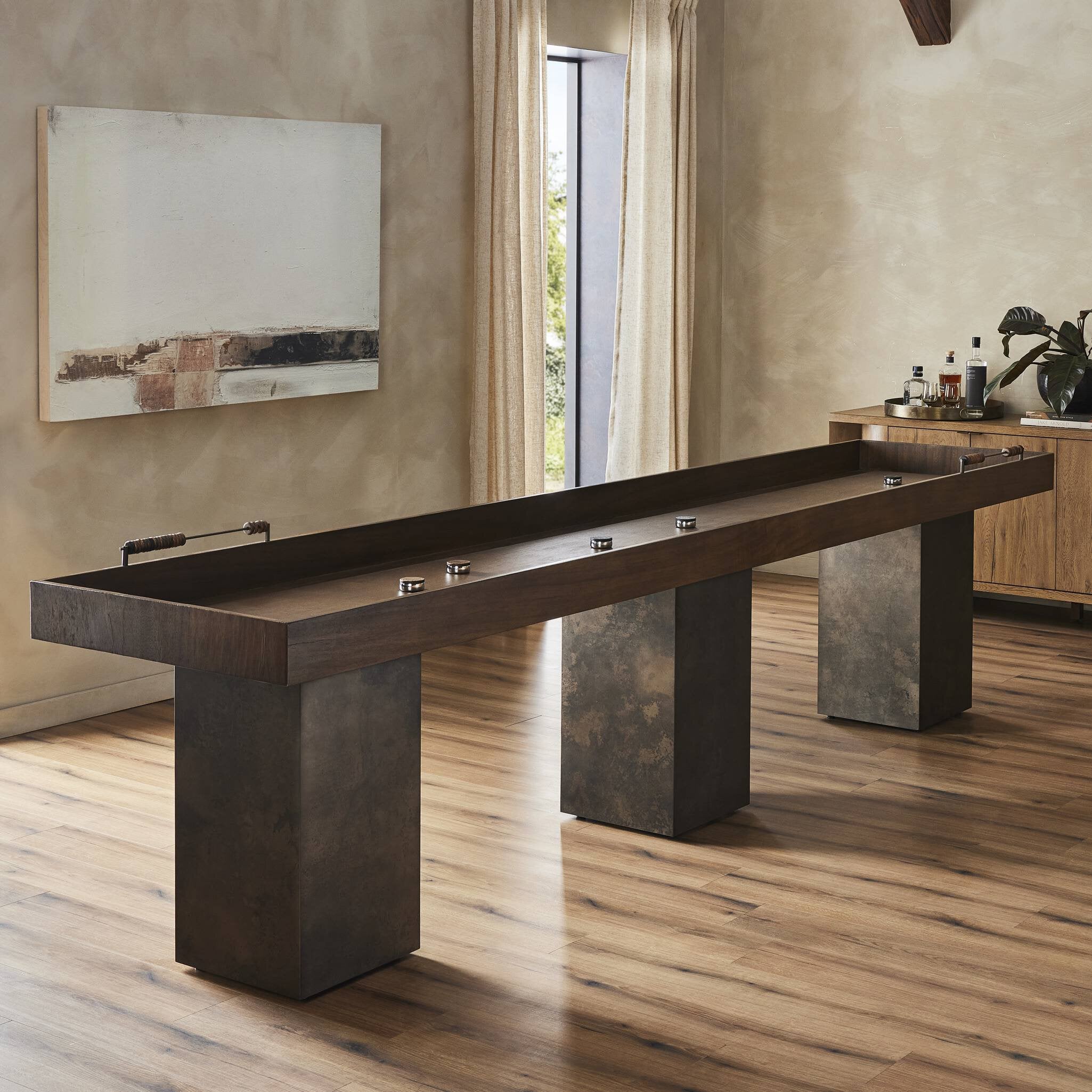 Featuring Shuffleboard Carbonized Black Table by Four Hands at Amethyst Home. This elevated shuffleboard table features a book-matched Guanacaste play surface with intricate laser-etched details, paired with steel and Guanacaste pucks. Aged metal accents highlight the design, all supported by three sleek, tapered bases. Regular care with shuffleboard waxes is required for optim. Amethyst Home provides interior design, new construction, custom furniture, and area rugs in the Laguna Beach metro area