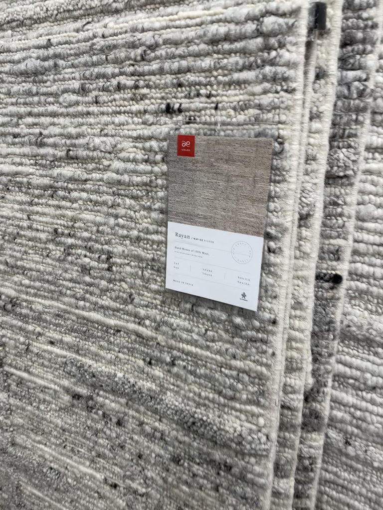 Hand-woven of 100% wool in India, the Rayan Silver Area Rug sets the tone for a calming atmosphere. Each design is crafted of textural highs and lows paired with neutral tones to create and engaging understatement. The perfect rug for your bedroom, office, or other medium traffic area.   Hand Woven 93% Wool | 5% Cotton | 2% Other Fibers Pile RAY-02 Silver