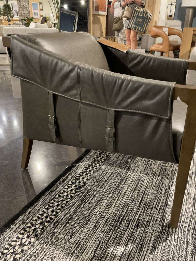 The Bauer Ebony Leather Chair is a favorite lush seating of ebony top-grain leather that fastens to grey birch framing via trend-forward buckles. The angular arms honor mid-century design, adding a throwback feel to a cutting-edge look.  Overall Dimensions: 27.00"w x 35.00"d x 29.00"h