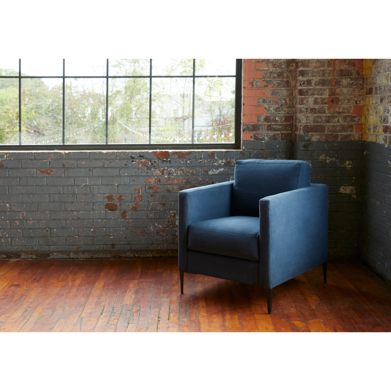 The Benedict Chair - Custom by Cisco Brothers is a modern design with clean lines and sleek metal legs in black rust. It has a fresh and functional aesthetic with no-sag support. As a small scale sofa, its ideal for apartment living and suitable for any occasion. Photographed in Mariet Marine. Amethyst Home provides interior design, new home construction design consulting, vintage area rugs, and lighting in the Houston metro area.
