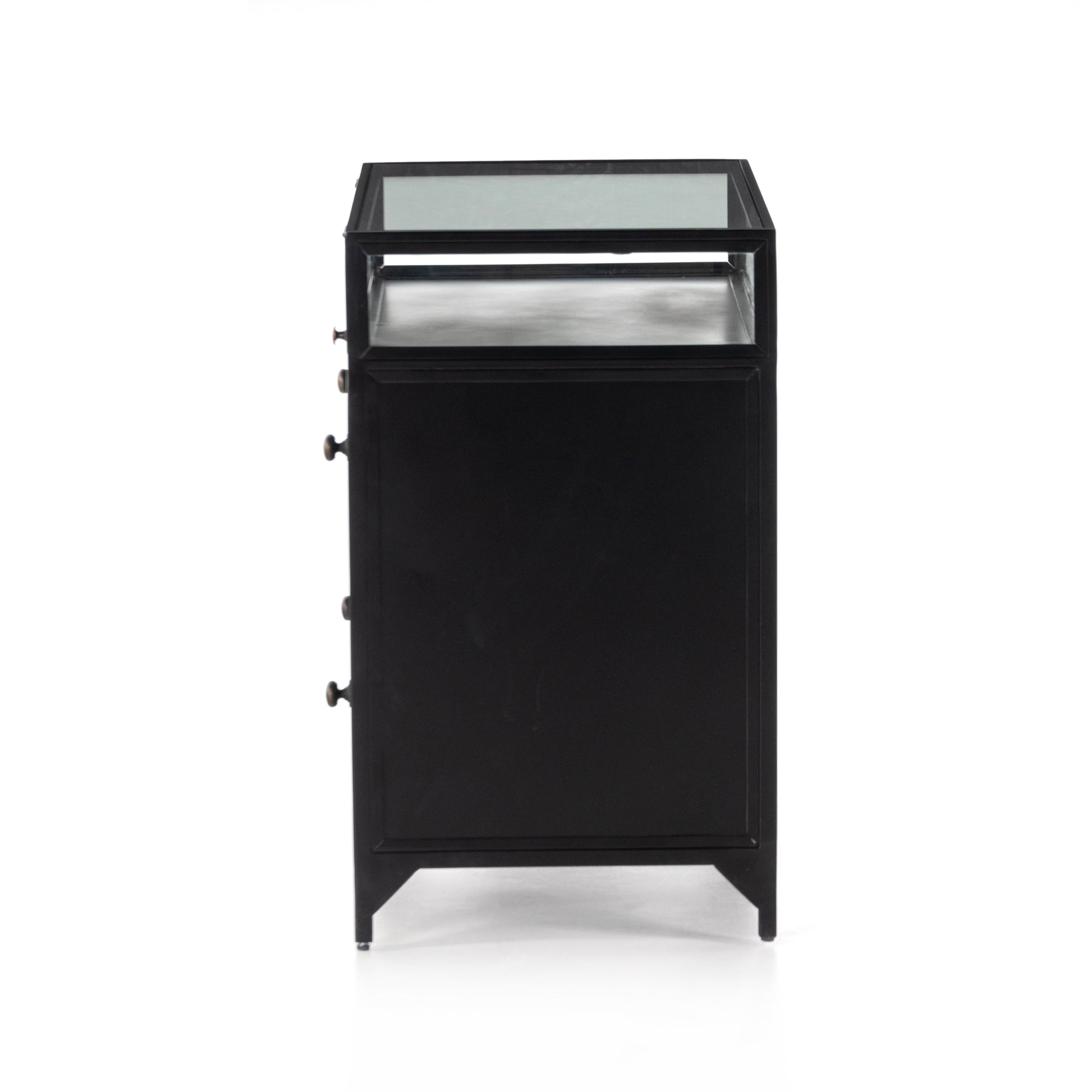 This Shadow Box Nightstand is finished in a gorgeous matte black. We love that the glass top allows you to showcase your favorite jewelry or family keepsake, while the two spacious drawers give you storage space. The knobs are finished in bronze to give this piece a sleek contrast.  Overall Dimensions: 28.00"w x 17.75"d x 30.00"h Materials: Iron, Tempered Glass, Glass