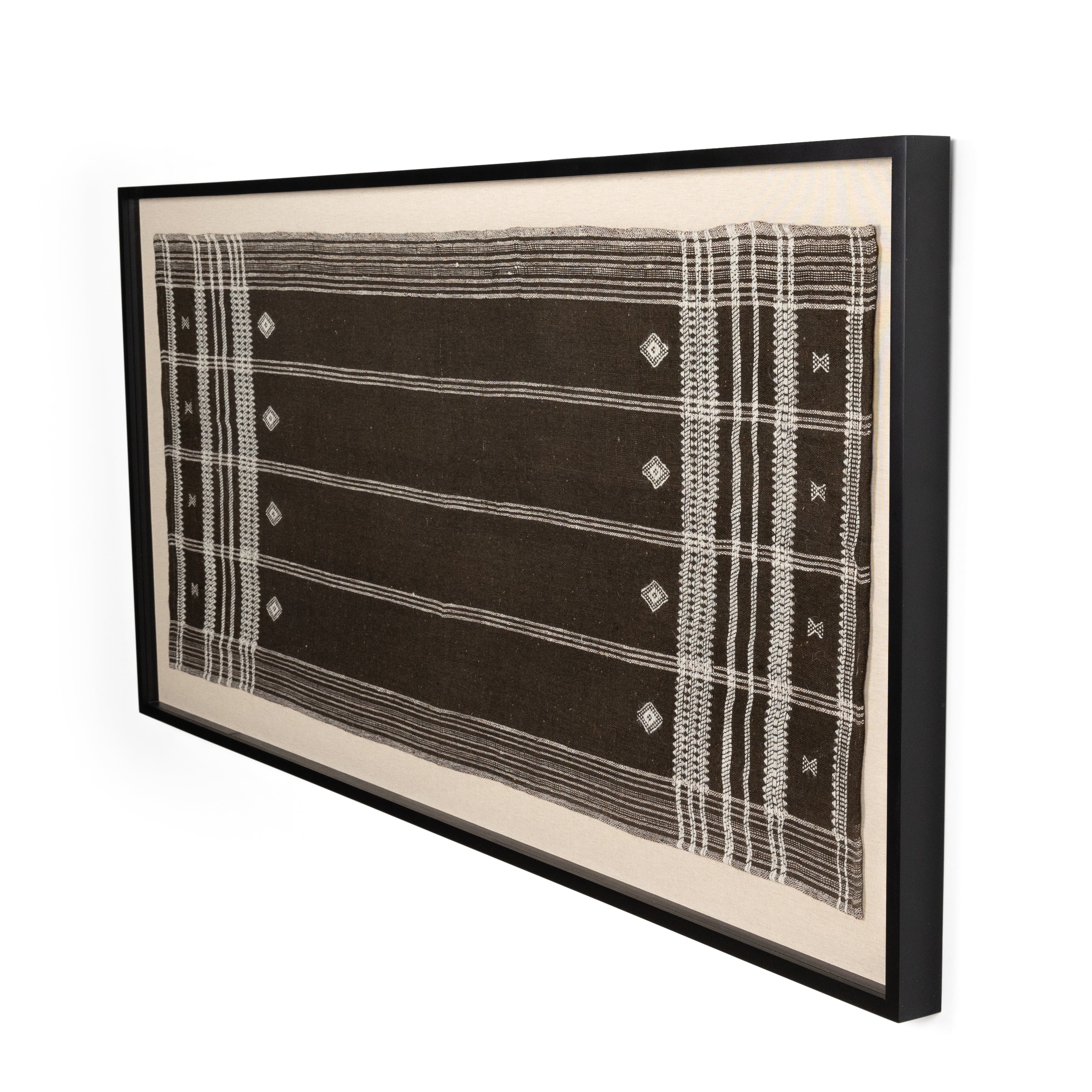 Featuring Bhujodi Chocolate Textile by Four Hands at Amethyst Home. A Bhujodi-style textile is framed within rustic walnut for a gallery-quality look. Handmade in Austin, Texas.Overall Dimensions: 75"W x 2.50"L x 35"HColors: Black 2.5 Maple, Bhujodi ChocolateMaterials: American Maple, 100% Wool. Amethyst Home provides interior design, new home construction design consulting, vintage area rugs, and lighting in the Portland metro area.