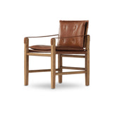 Inspired by a vintage safari-style frame, this dining chair is defined by the fluid strap arms. Semi-attached cushions in rich chestnut leather, finished with button tufting details. Parawood frame and brass details add warmth and texture.Collection: Westgat Amethyst Home provides interior design, new home construction design consulting, vintage area rugs, and lighting in the Alpharetta metro area.