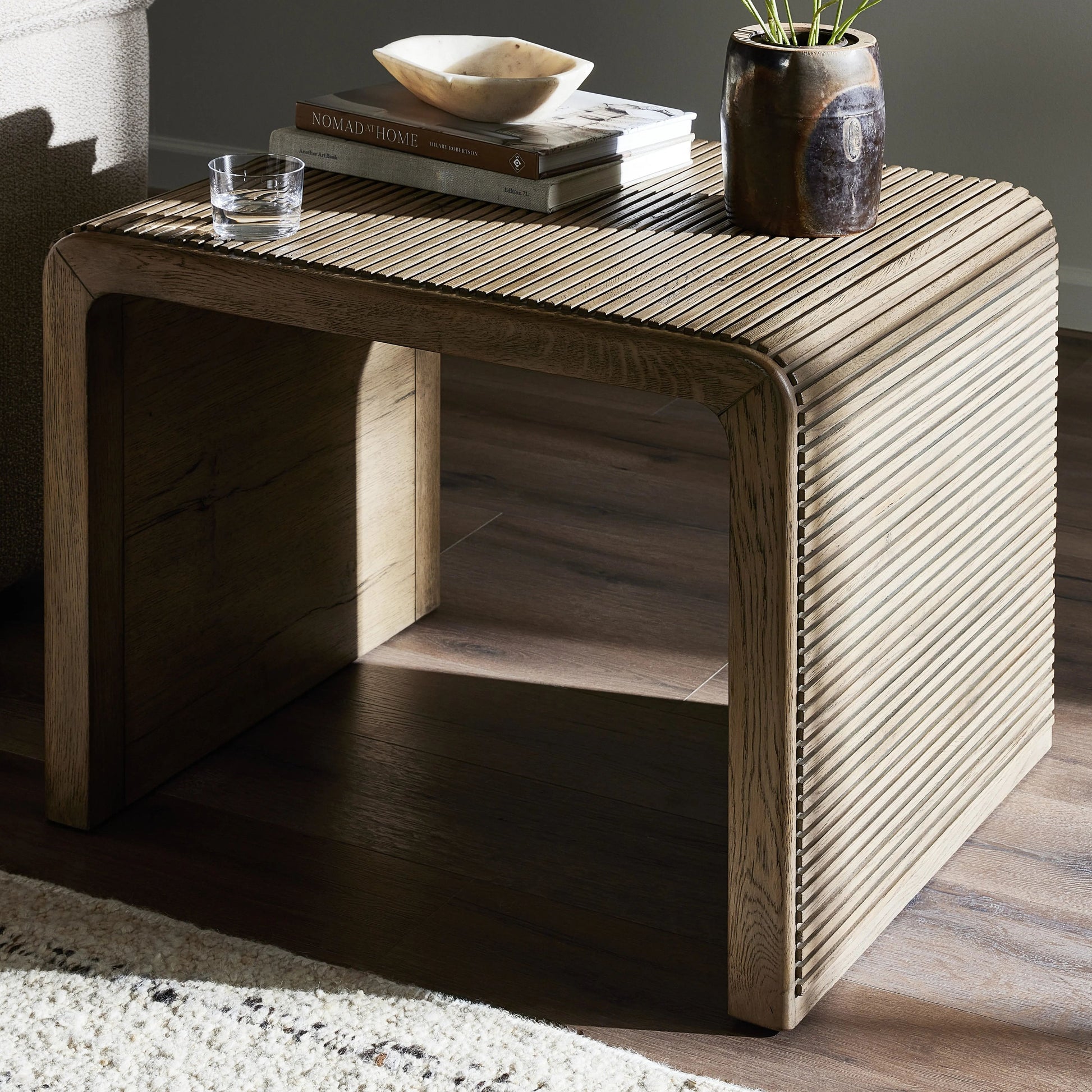 Made from rustic-finished oak, linear reeding and a curved shape define this midcentury-spirited end table. Designed in partnership with longtime Four Hands collaborator Thomas Bina and Brazilian designer Ronald Sasson.Collection: Bin Amethyst Home provides interior design, new home construction design consulting, vintage area rugs, and lighting in the Portland metro area.