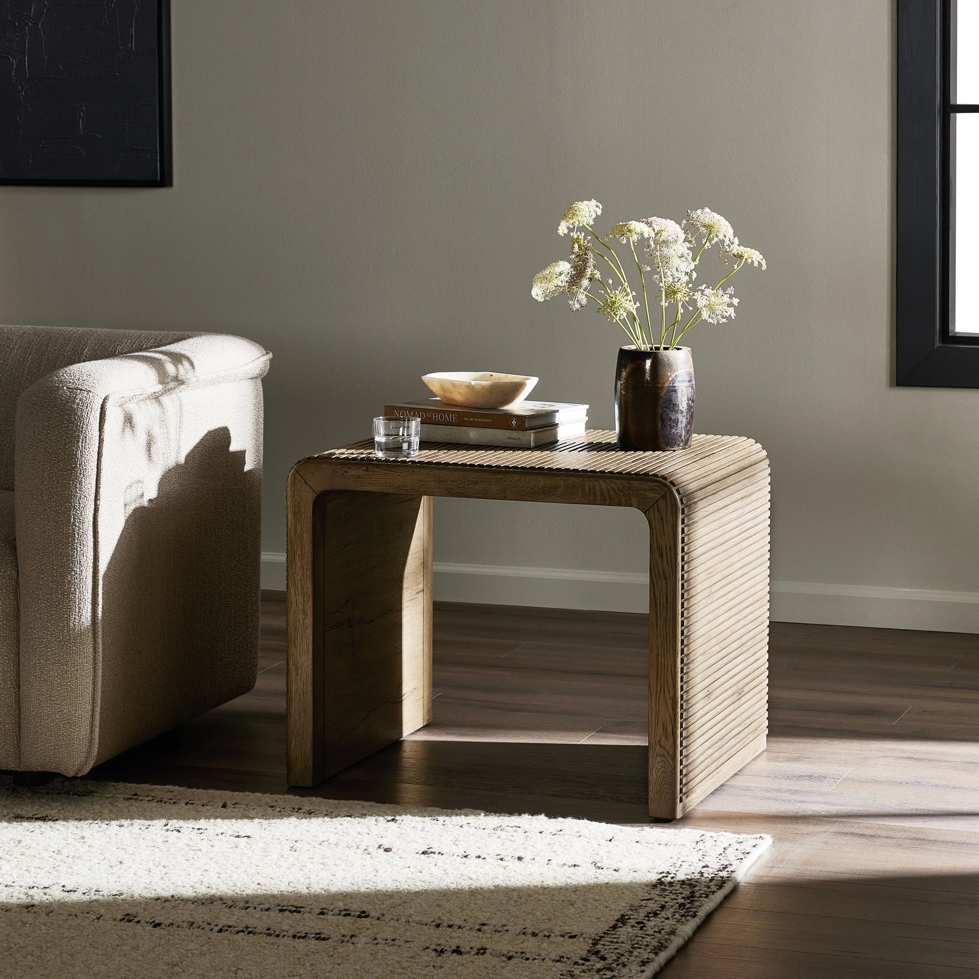 Made from rustic-finished oak, linear reeding and a curved shape define this midcentury-spirited end table. Designed in partnership with longtime Four Hands collaborator Thomas Bina and Brazilian designer Ronald Sasson.Collection: Bin Amethyst Home provides interior design, new home construction design consulting, vintage area rugs, and lighting in the Seattle metro area.