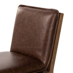 Inspired by the folded pillow form, the seat and back cushions of this oak dining chair are covered in brown top-grain leather. The chair back features leather strap details for a mixed material touch.Collection: Ashfor Amethyst Home provides interior design, new home construction design consulting, vintage area rugs, and lighting in the Houston metro area.