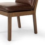 Inspired by the folded pillow form, the seat and back cushions of this oak dining chair are covered in brown top-grain leather. The chair back features leather strap details for a mixed material touch.Collection: Ashfor Amethyst Home provides interior design, new home construction design consulting, vintage area rugs, and lighting in the Laguna Beach metro area.