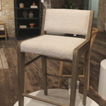 We love the mixed materials found in this Charon Bar + Counter Stool. In a light, natural finish, solid parawood forms an angular frame for boucle-upholstered seating in a classic cream.
