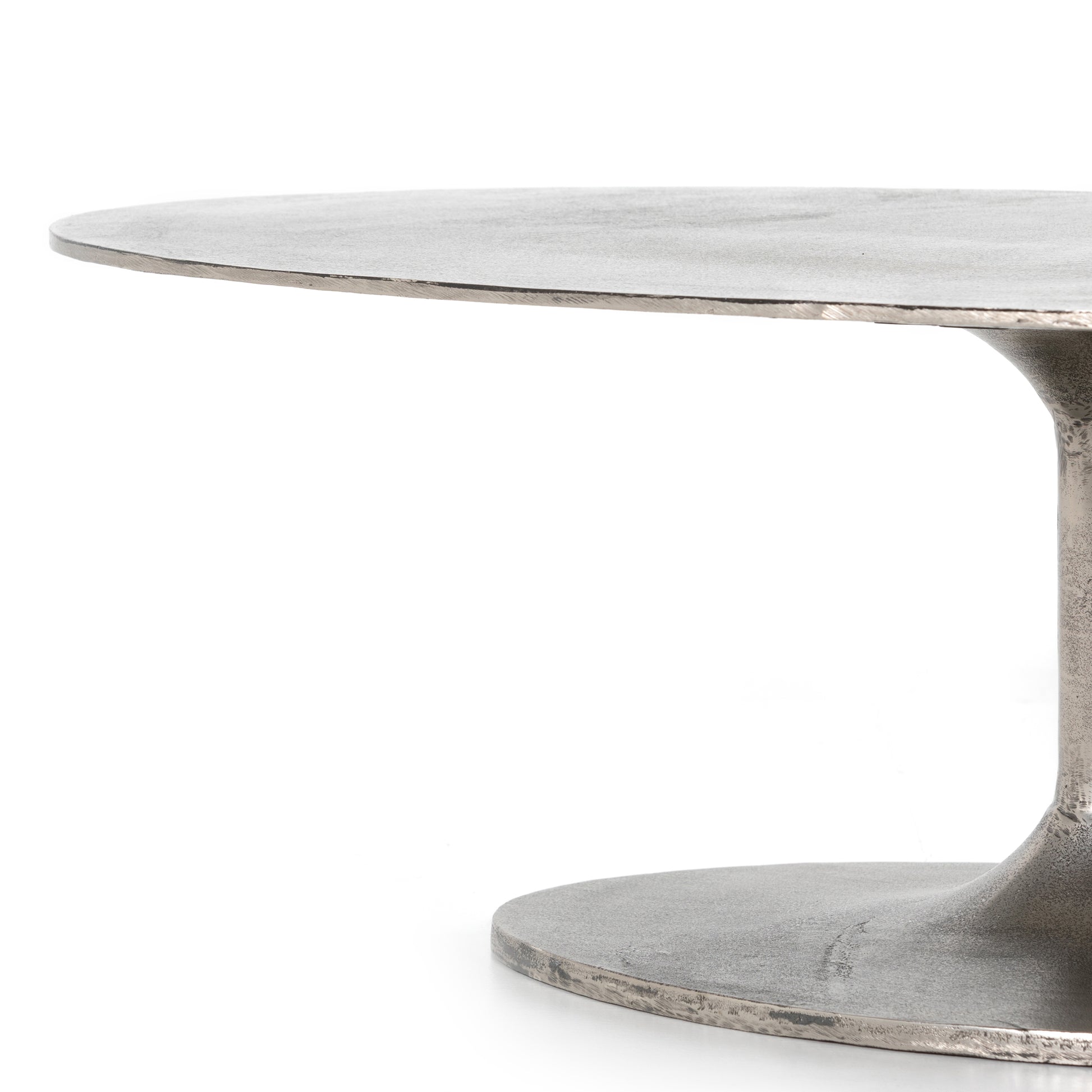 We love the oval shape of this Simone Coffee Table - Antique Nickel. The textural cast aluminum makes for a beautifully modern coffee table, with alluring highs and lows played up by a raw nickel finish. Great indoors or out; cover or store indoors during inclement weather and when not in use.  Overall Dimensions: 54.75"w x 29.25"d x 16.50"h