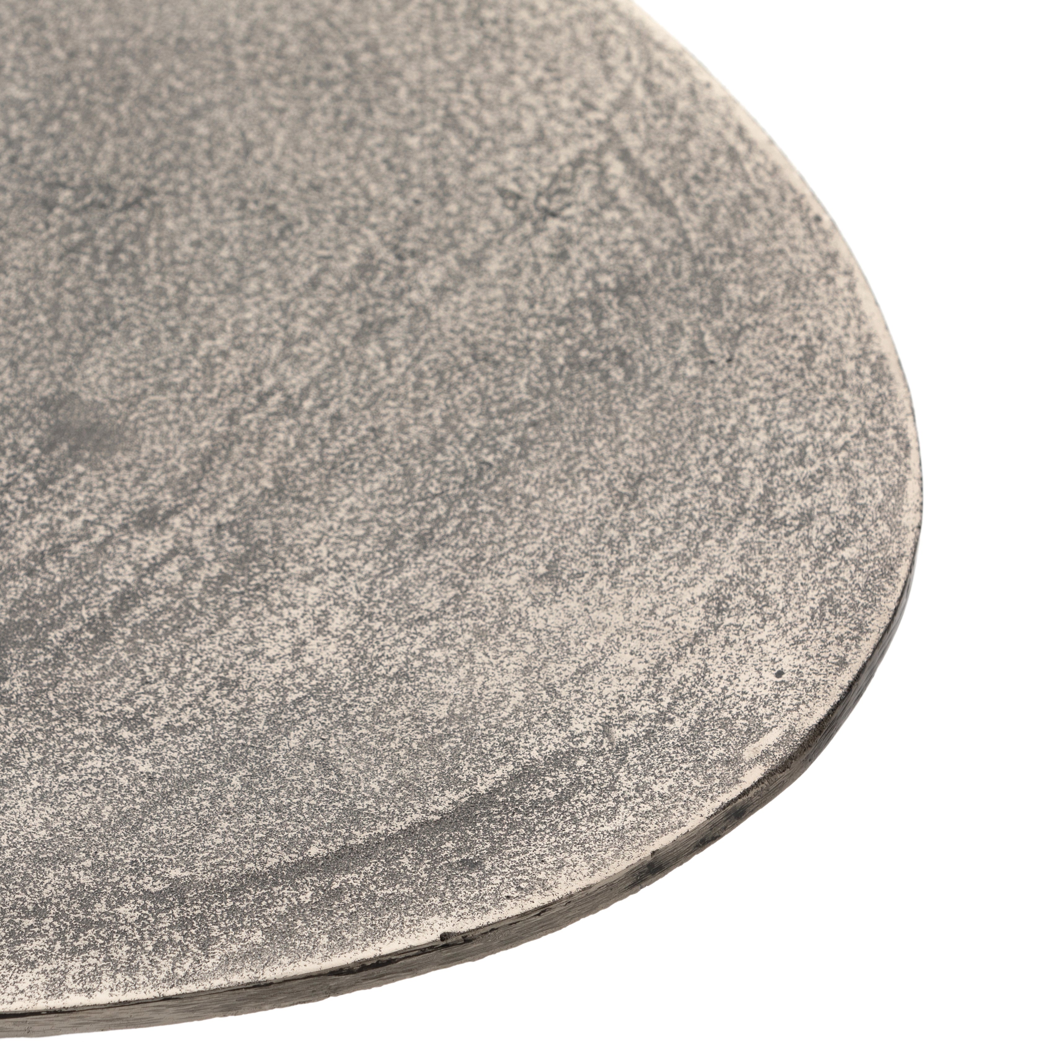 We love the oval shape of this Simone Coffee Table - Antique Nickel. The textural cast aluminum makes for a beautifully modern coffee table, with alluring highs and lows played up by a raw nickel finish. Great indoors or out; cover or store indoors during inclement weather and when not in use.  Overall Dimensions: 54.75"w x 29.25"d x 16.50"h
